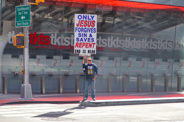 A photo of a man with a giant Jesus sign in Times Square